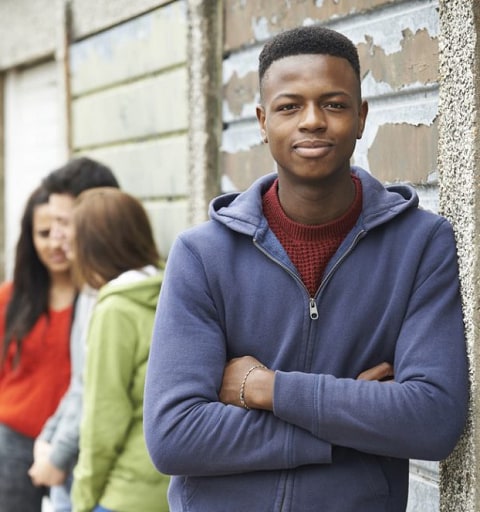 smiling young man standing in front of group of friends