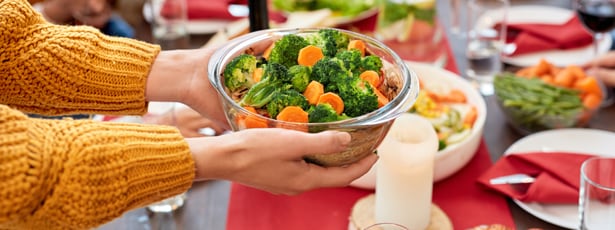 Person passing a bowl of vegetables
