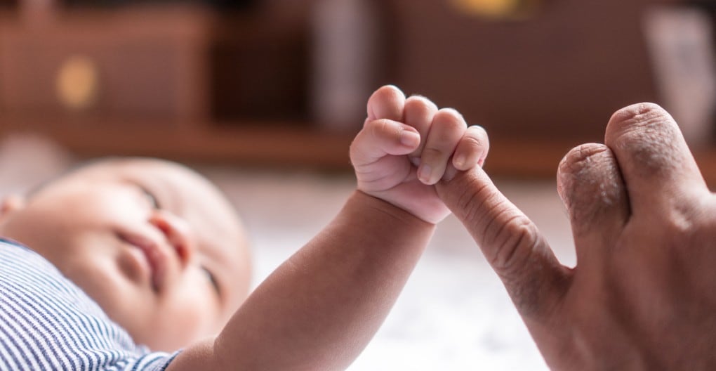 Baby holding parent's pinky finger
