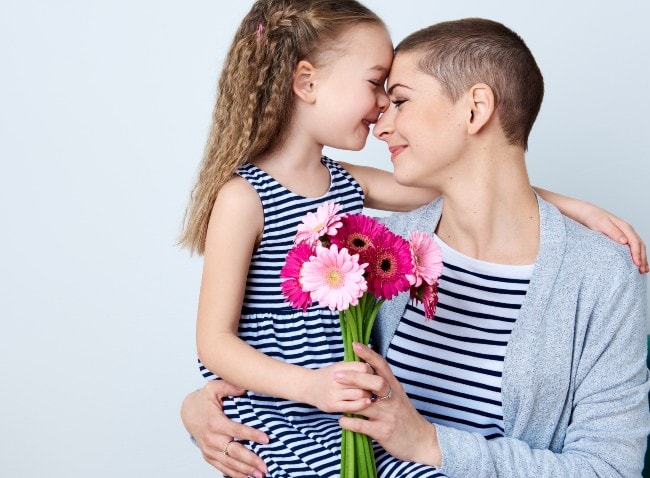 Daughter giving mother flowers as they embrace