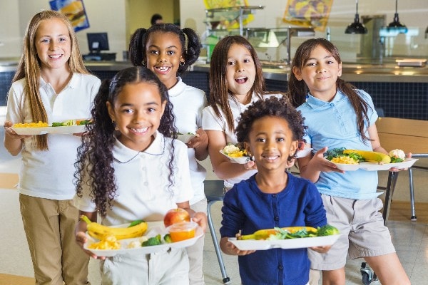 diverse group of girls holding healthy lunches at school