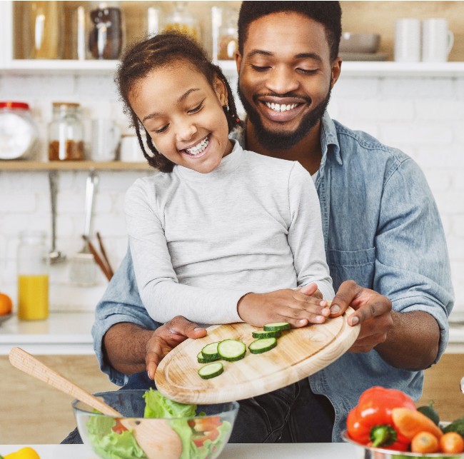 Girl and her father making salad together.