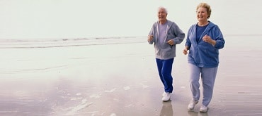 portrait of senior couple jogging on the beach