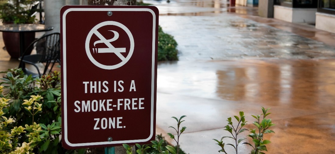 This is a smoke free building sign posted on brick wall.