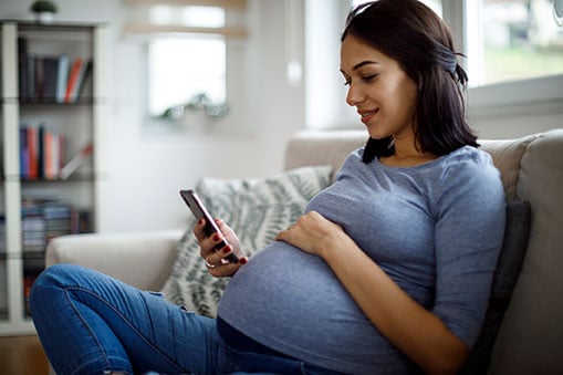 Mujer embarazada investigando sobre el CMV en su celular