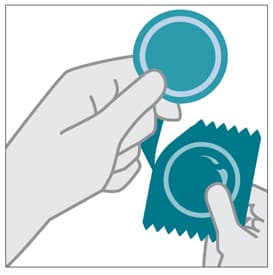 Manos presionando la punta del condón para eliminar el aire