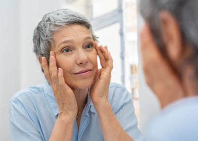 Older woman examining her eyes
