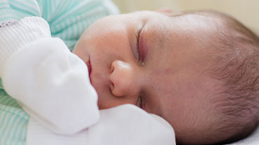 Sleeping baby wearing mittens.