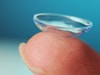 contact lens on a fingertip with a dark blue background