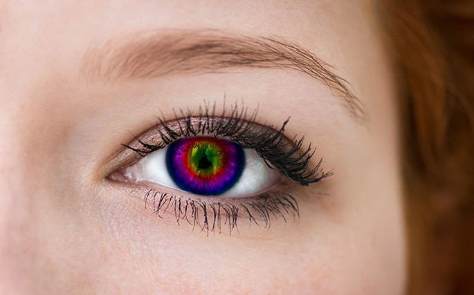 Close up image of a woman's eye with a multicolored contact lens.