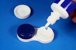 a multipurpose solution bottle being used to clean contacts that are sitting in a storage case.