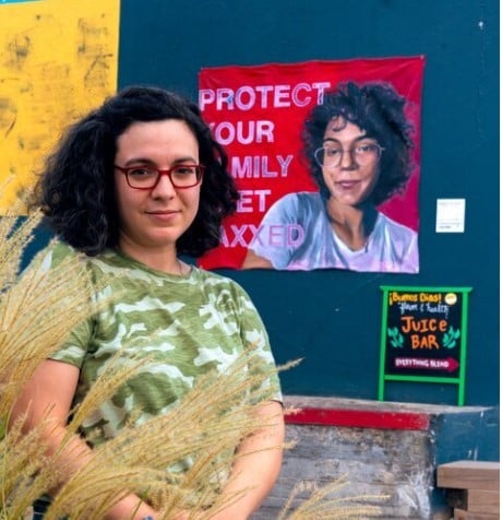 Photo of artist Angela Bortone, standing in front of her artwork.