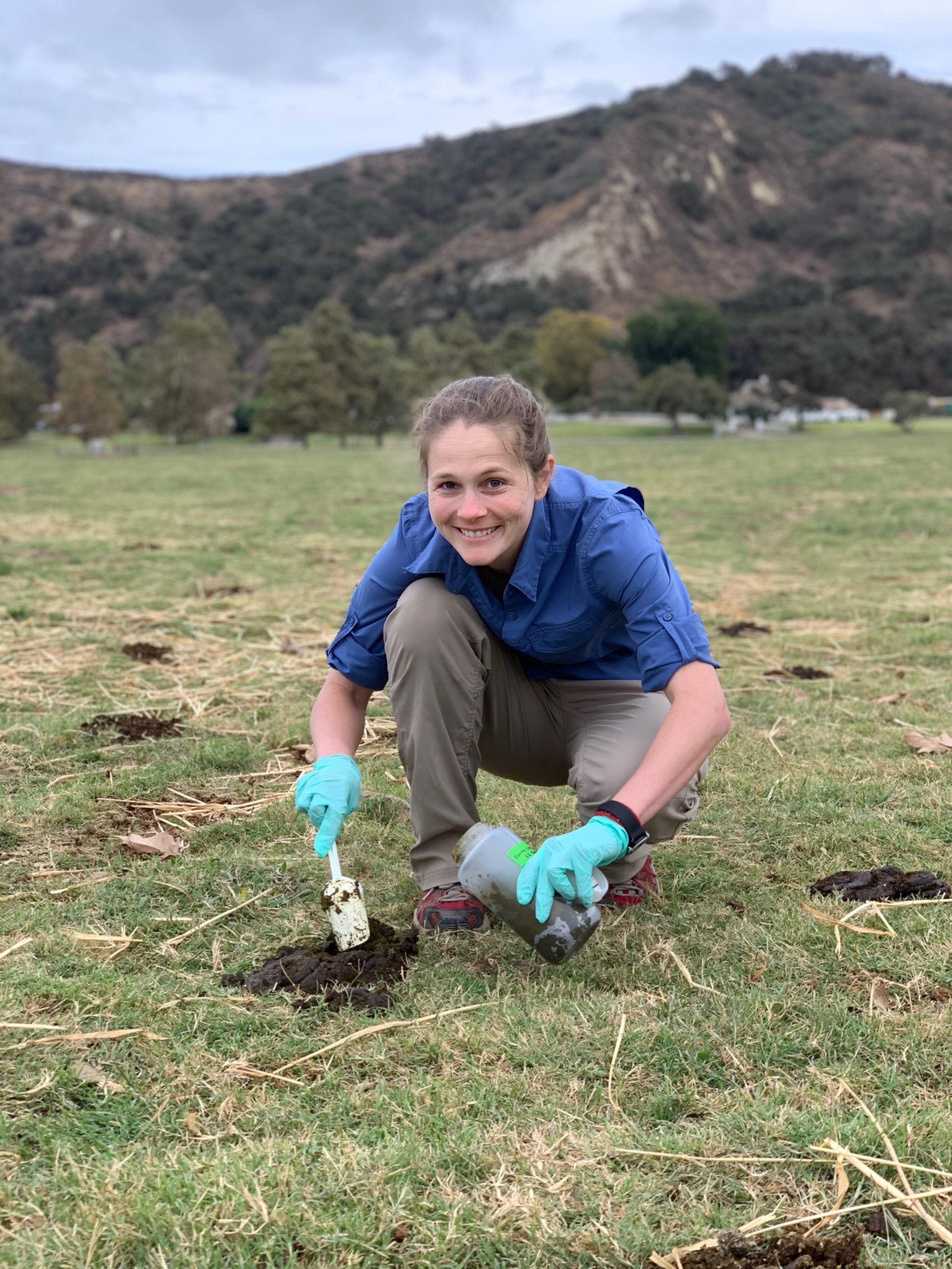 A photo of CDC environmental engineer Mia Mattioli kneeling in a field collecting samples cattle feces.