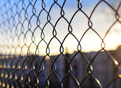 Image of chain link fence with prison in background