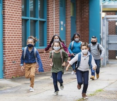 niños de primaria salen de la escuela con sus mascarillas puestas