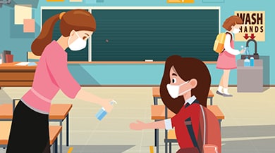 maestra le ofrece desinfectante de manos a una estudiante en el salón de clase