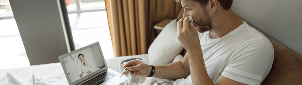 man doing telehealth call sick in bed