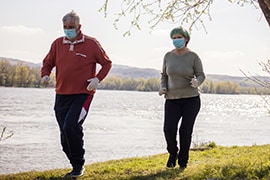 two walkers outside by lake wearing cloth face masks