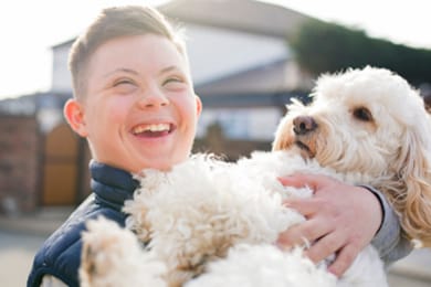 Foto de un niño con una discapacidad sosteniendo a un perro.