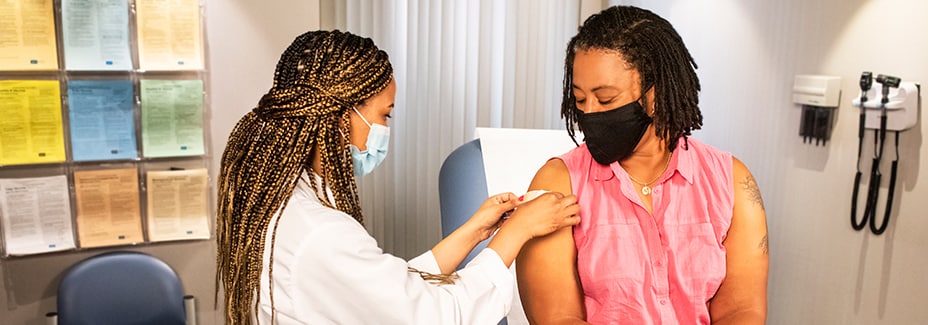 health care professional applying a bandage to a patient after a vaccine
