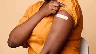 Hình chụp cận cảnh cánh tay người phụ nữ da màu có dán băng keo sau khi tiêm chủng