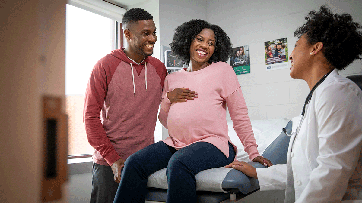 How to protect yourself and others Young Black family - dad and pregnant mom at the doctor's office, smiling