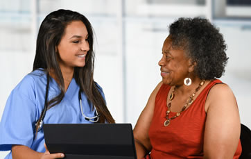 Medical professional speaking with a patient in front of a tablet