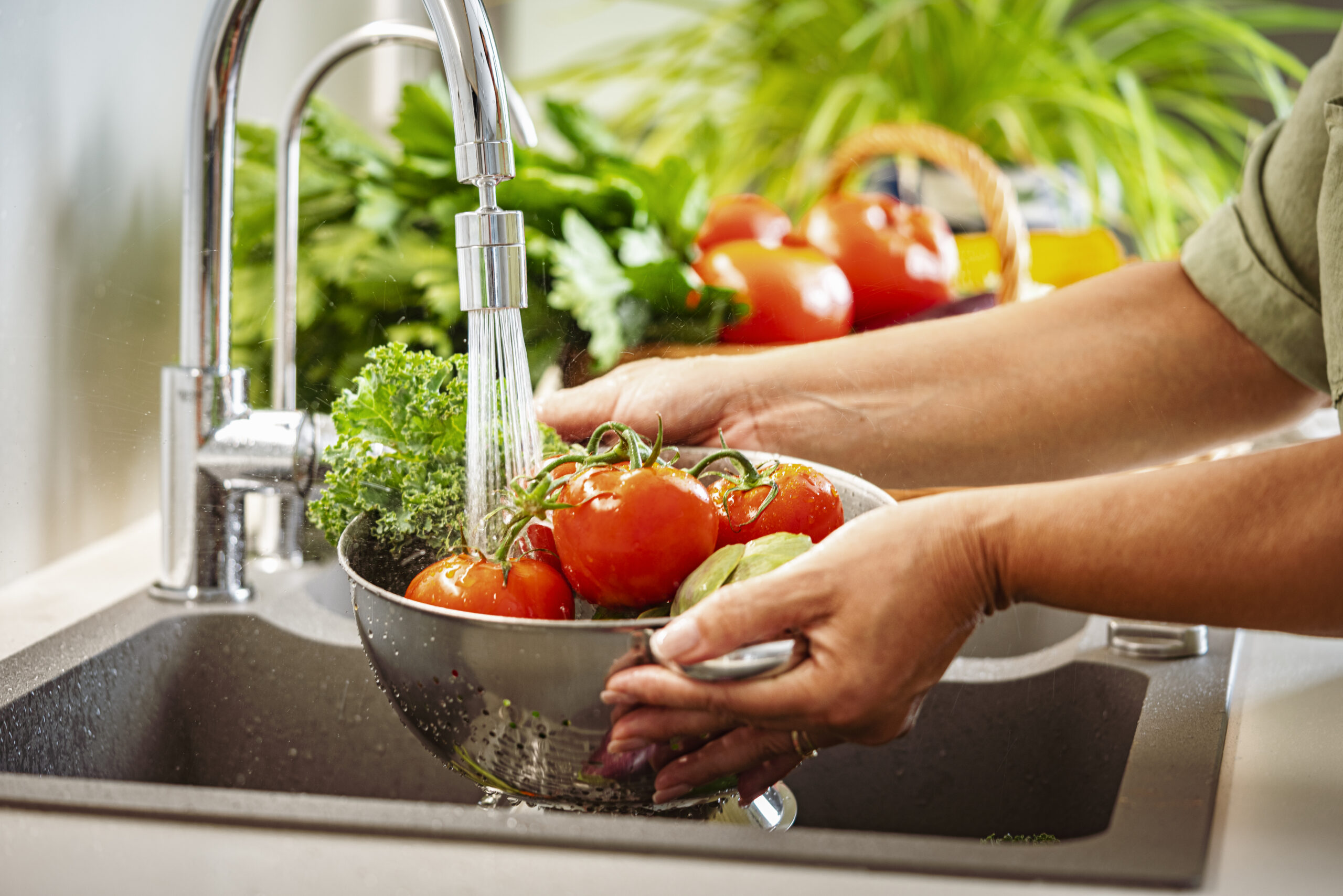 Person rinsing vegetables under water.