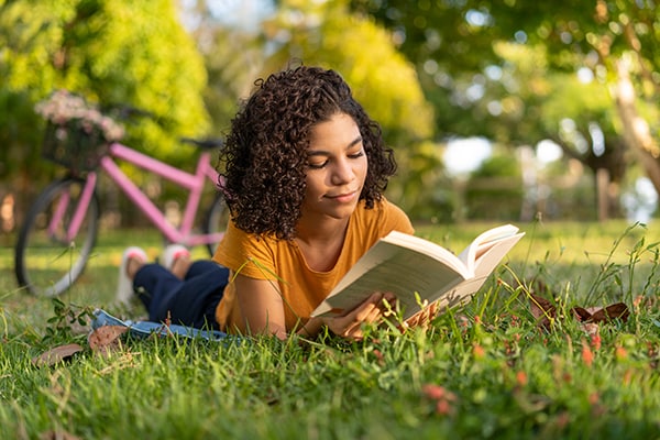 Girl reading a book while outdoors.