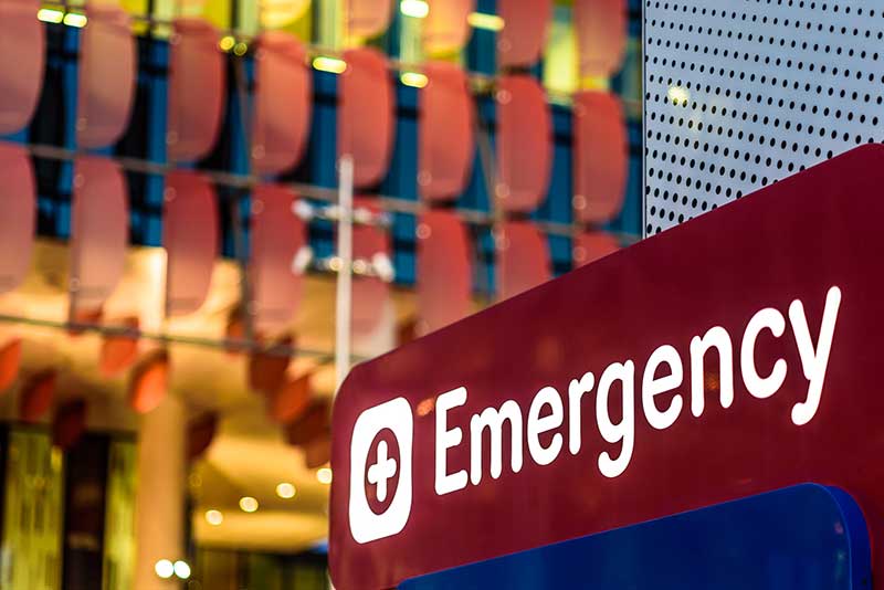 An imagine of an emergency room sign in front of a hospital.
