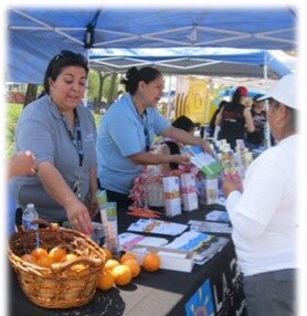 CHWs handing out healthy fruit to people at an outdoor event.