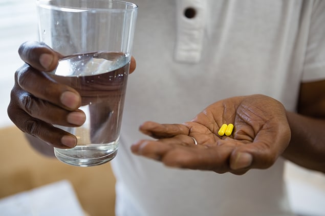 Person taking medication with a glass of water.