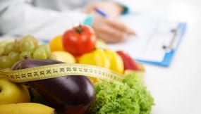 Fruits and vegetables, a measuring tape and a provider writing on a clipboard in the background.