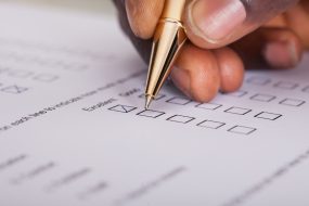 Close-up of a hand filling out a survey form