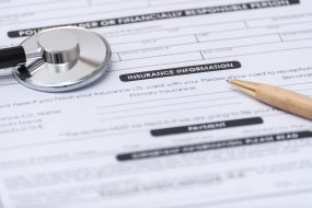Close-up of Health Insurance Claim Application Form with pen and stethoscope