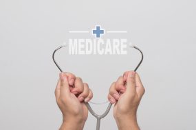 Hands holding a stethoscope and word  "MEDICARE" on gray background. concept Healthy.