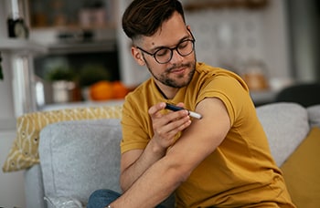 man on couch using insulin pen