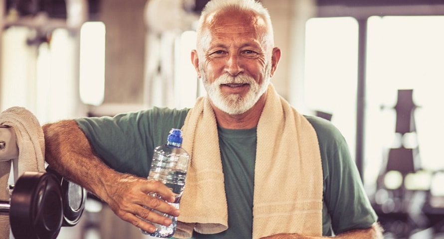 Older man in gym drinking a bottle of water