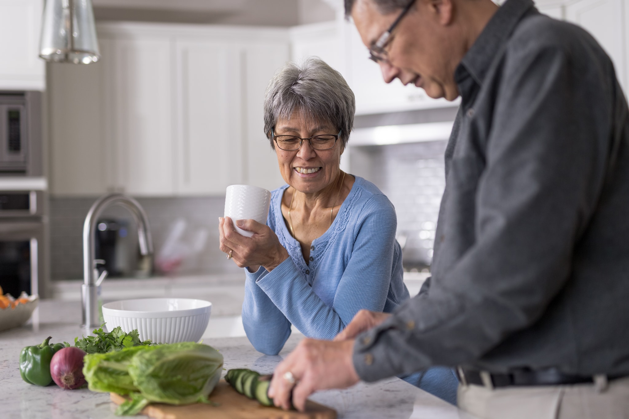 older male preparing a healthy meal for older woman.