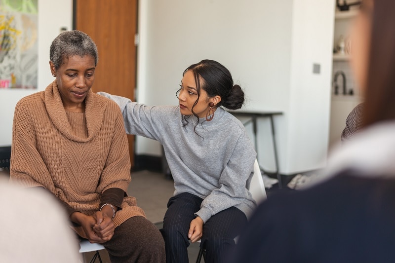 Woman showing support for another woman in a therapy session.
