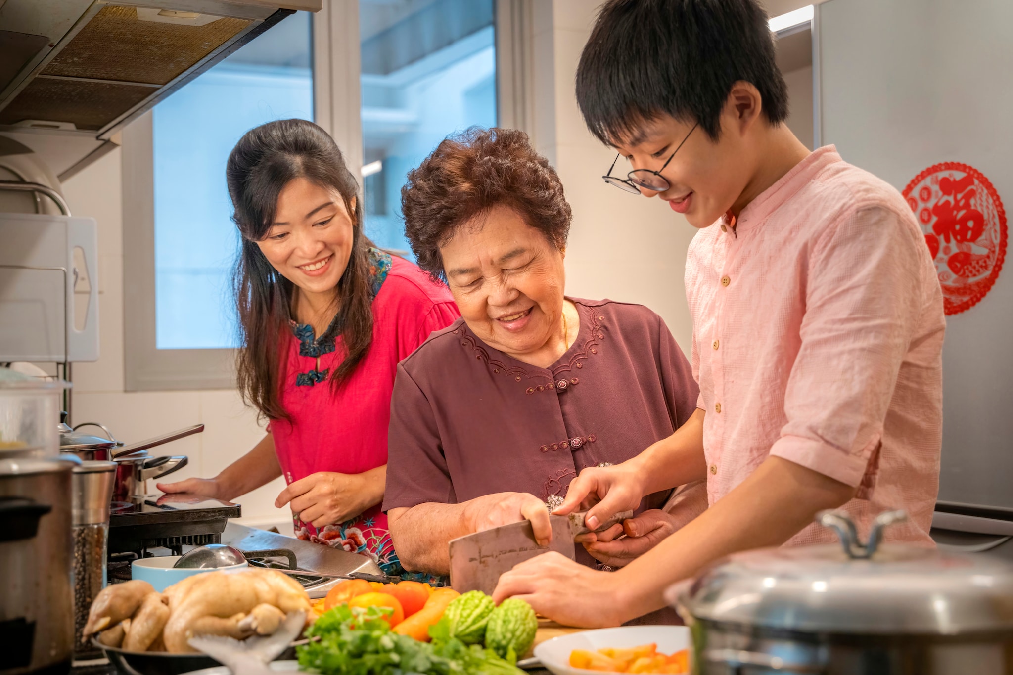 Young Asian male learning how to prepare food from his mother and grandmother.