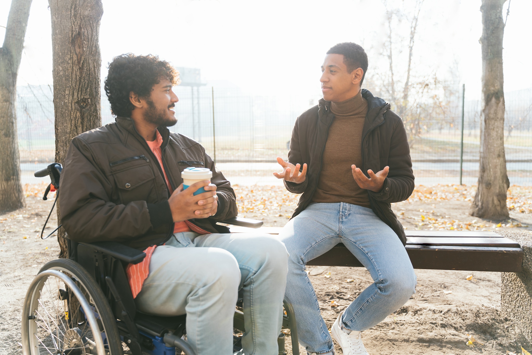 Dos jóvenes adultos sentados afuera, conversando.