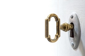 Old key in keyhole, macro shot, white background.