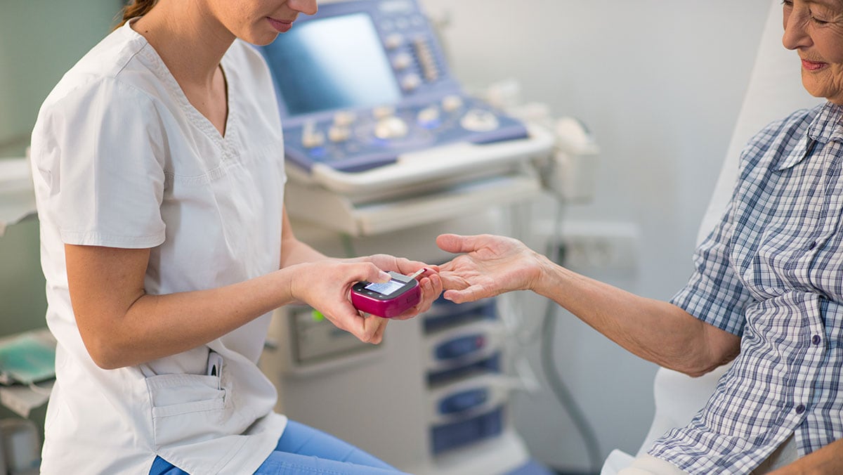 Nurse giving an elderly patient a diabetes test