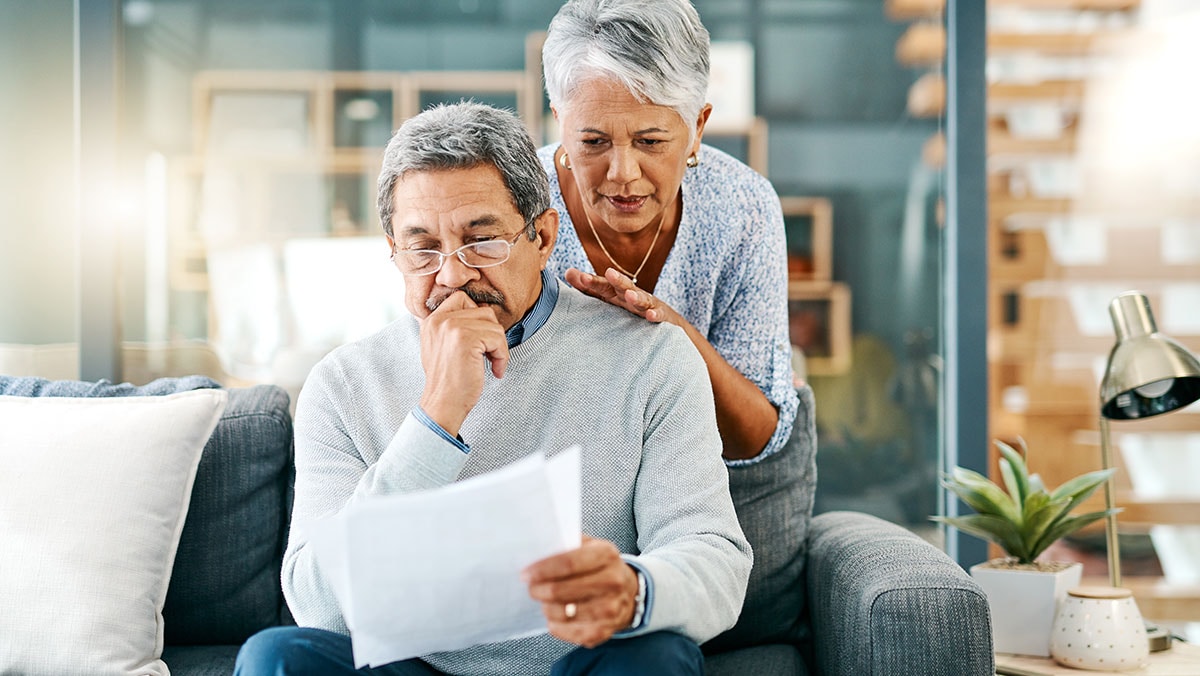 mature couple looking worried while going through paperwork together at home