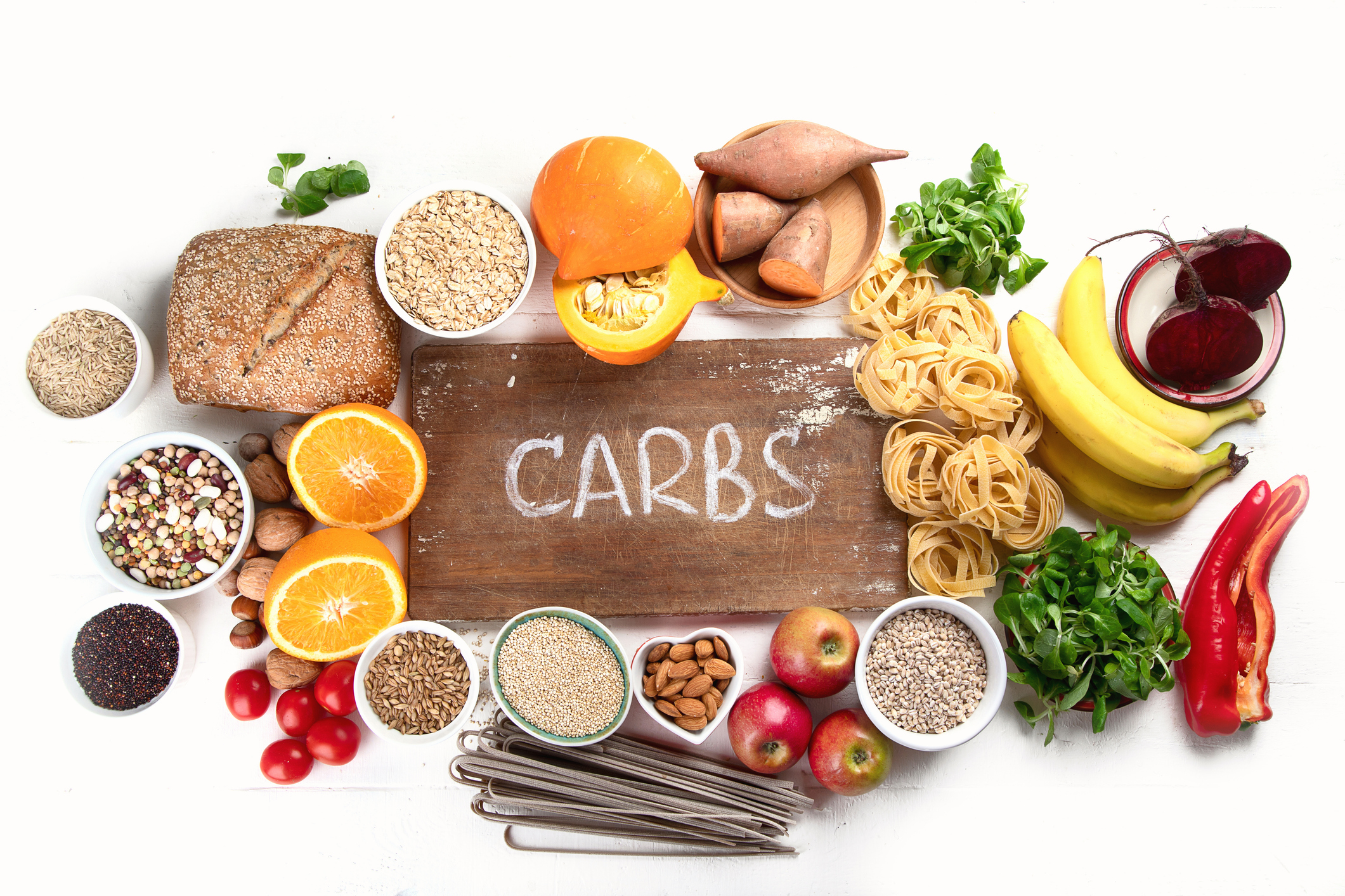 Wooden sign with the word "carbs" surrounded by various carbs discussed in the article