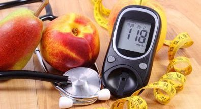 fruta, un monitor de diabetes, pesas y una cinta métrica