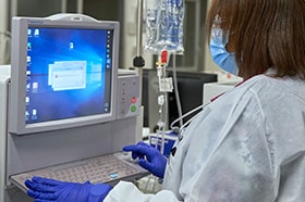 Healthcare worker wearing PPE at a computer terminal