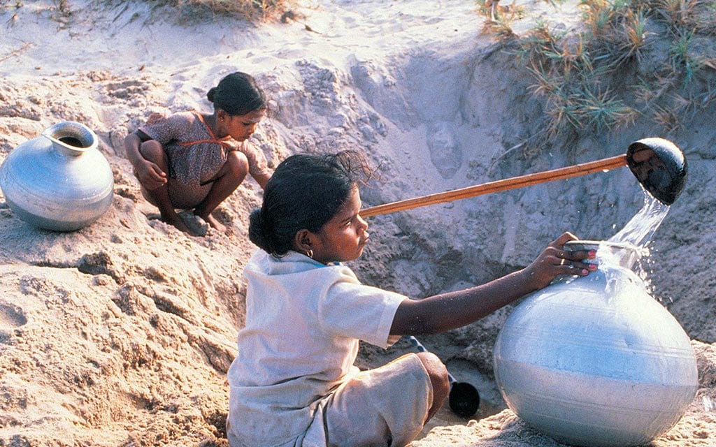 Village children fill water containers at the common village well.
