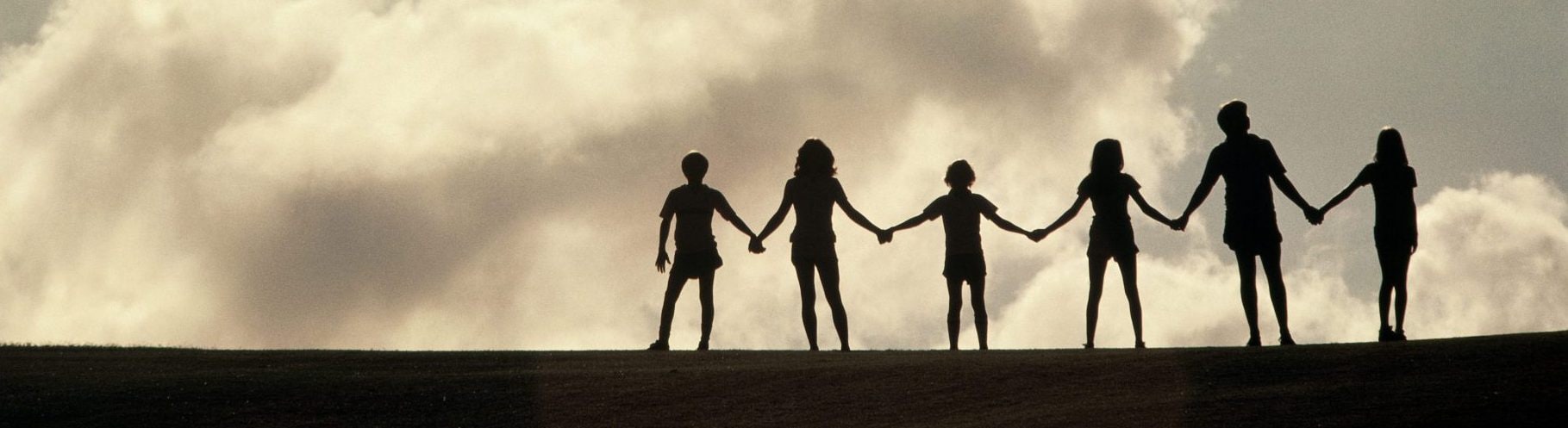 silhouette of family holding hands on top of a hill